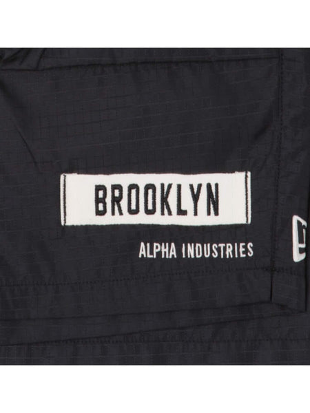 A close-up of the black ripstop fabric features a rectangular patch with "Brooklyn" and beneath it, the "Alpha Industries" text, echoing the durability typically associated with Alpha Industries gear like the Brooklyn Nets x Alpha x New Era Nylon Shorts.