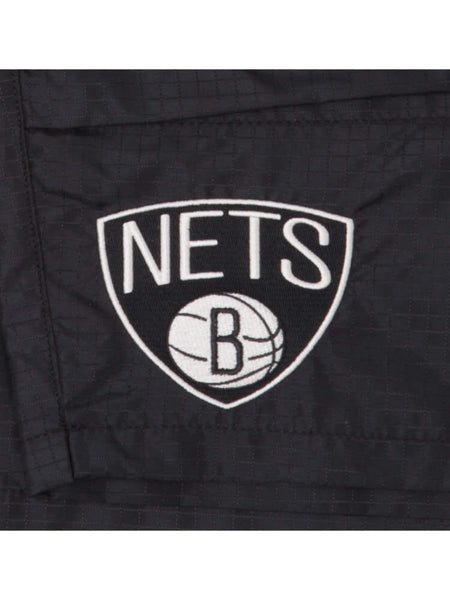 Close-up of the black ripstop fabric showcasing the Brooklyn Nets logo above a basketball with the letter B inside, evocative of Alpha Industries: Brooklyn Nets x Alpha x New Era Nylon Shorts.