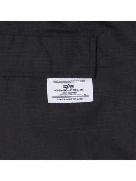 Label on a black ripstop fabric with text: Alpha Industries / NE-NBA, Brooklyn Nets x Alpha x New Era Nylon Shorts, Plant Manufacturing Data Code 3J290, Do Not Remove This Label.
