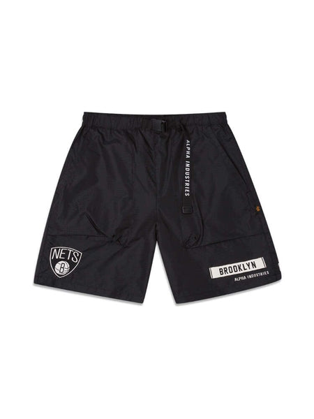 Alpha Industries / NE-NBA Presents the Black Brooklyn Nets x Alpha x New Era Nylon Shorts. With Brooklyn Nets and Alpha Industries logos, these shorts feature side pockets and an adjustable belt. Made from durable ripstop fabric, they're ideal for NBA fans seeking style and functionality.
