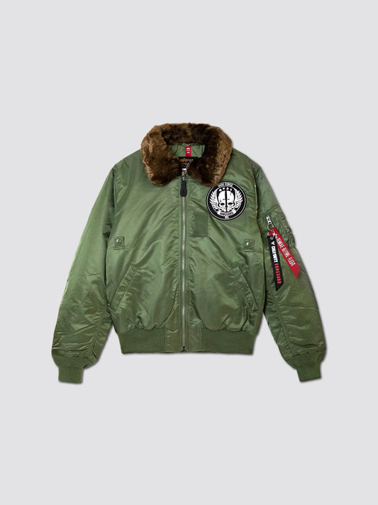 This sage bomber jacket, reminiscent of the iconic B-15 Flight Jacket, features a brown fur collar, zipper closure, and a circular embroidered patch on the chest. It also boasts a red "Remove Before Flight" tag on the sleeve. This is the Call Of Duty X Alpha B-15 Slim Fit Jacket by Alpha Industries, Inc.