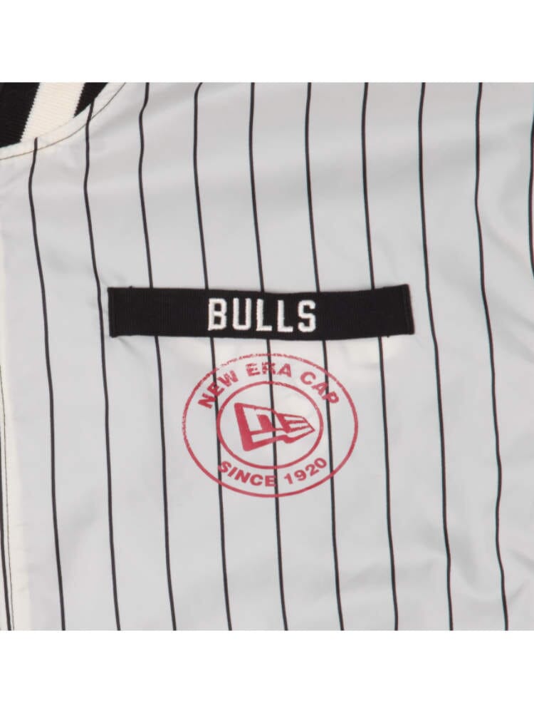 The Chicago Bulls x Alpha x New Era L-2B Bomber Jacket features pinstriped fabric with "BULLS" text on a black patch, complemented by a red "New Era Cap Since 1920" logo below, capturing the unique style of the Alpha Industries and NE-NBA collaboration, reminiscent of an iconic NBA Bomber Jacket with distinctive team patches.