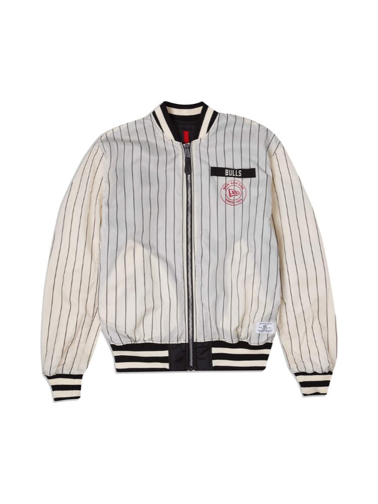 The Chicago Bulls x Alpha x New Era L-2B Bomber Jacket by Alpha Industries, featuring a white and black striped design with Bulls and a red logo on the chest, complemented by ribbed cuffs and waistband.