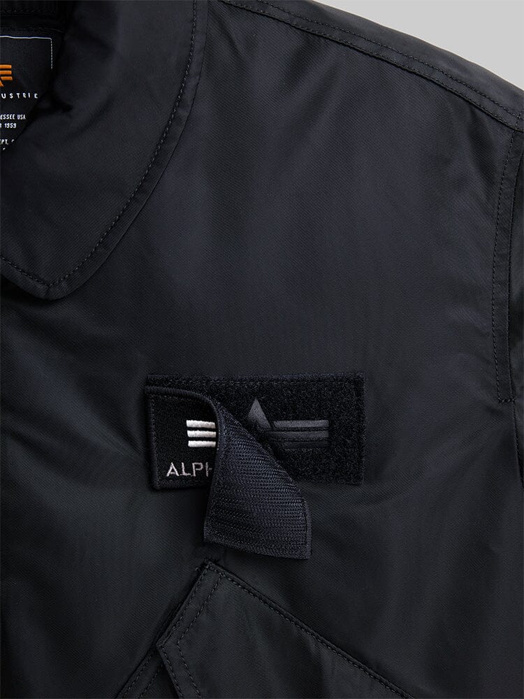 Alpha Industries Cwu 45/P Bomber Jacket with black Velcro patch, embroidered white and gray stripes, "Alpha" partially hidden.