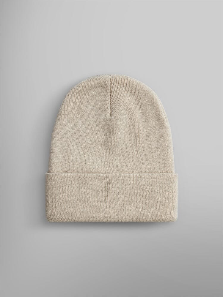 The Essential Beanie from Alpha Industries, Inc. is showcased, highlighting its beige knit design with a folded brim and an Alpha Industries paper label for added style.