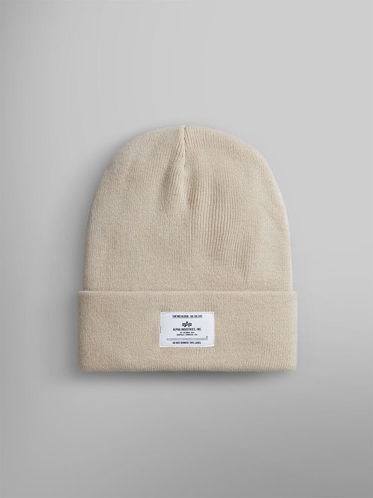 Limestone knit beanie with a folded brim and an Alpha Industries, Inc. label featuring text and a small logo.