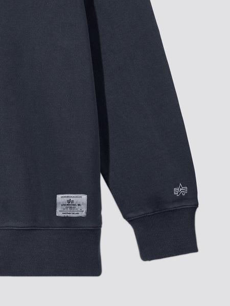 Essential Washed Crewneck by Alpha Industries, dark navy, ribbed cuff, small embroidered logo near hem, rectangular fabric label.