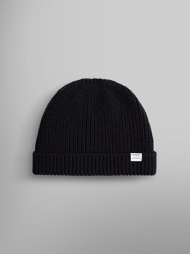 Introducing the Essential Watch Cap by Alpha Industries: a black wool-blend knitted beanie with a rolled cuff and adorned with a small white logo tag, inspired by the timeless military classic.