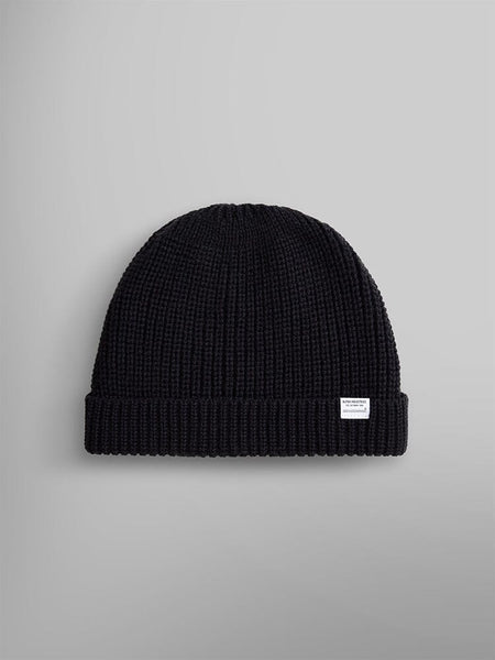 Introducing the Essential Watch Cap by Alpha Industries: a black wool-blend knitted beanie with a rolled cuff and adorned with a small white logo tag, inspired by the timeless military classic.