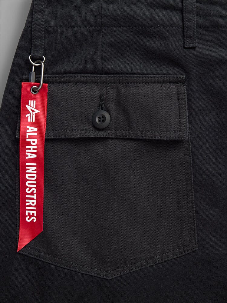 Fatigue Pant by Alpha Industries, black cotton fabric, button flap pocket, red Alpha Industries tag on metal clasp, utility pockets.