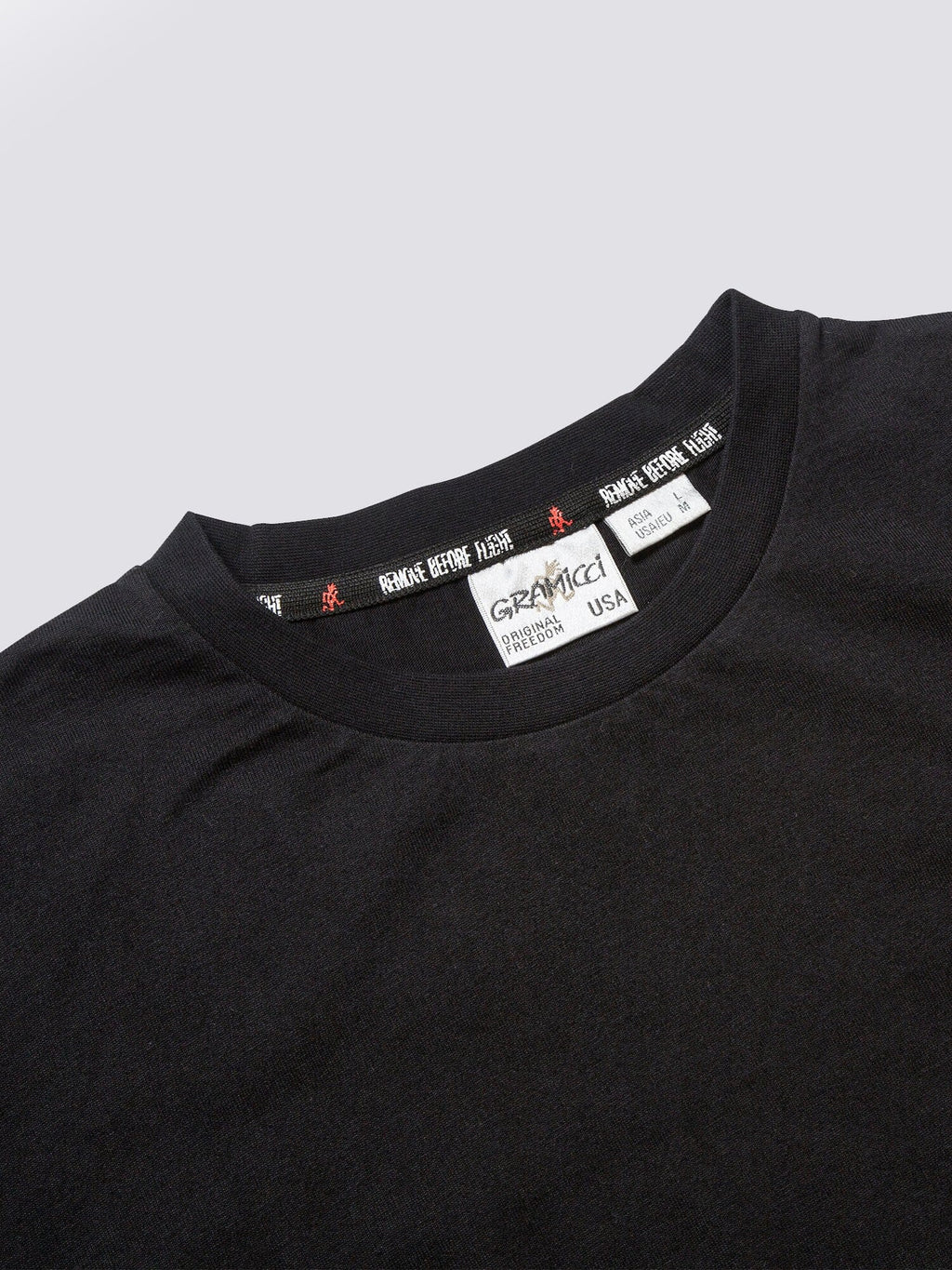 Gramicci X Alpha Cotton Cigar Pocket Tee by Alpha Industries, black crewneck collar, branded label with size and origin details, utility pocket on sleeve.
