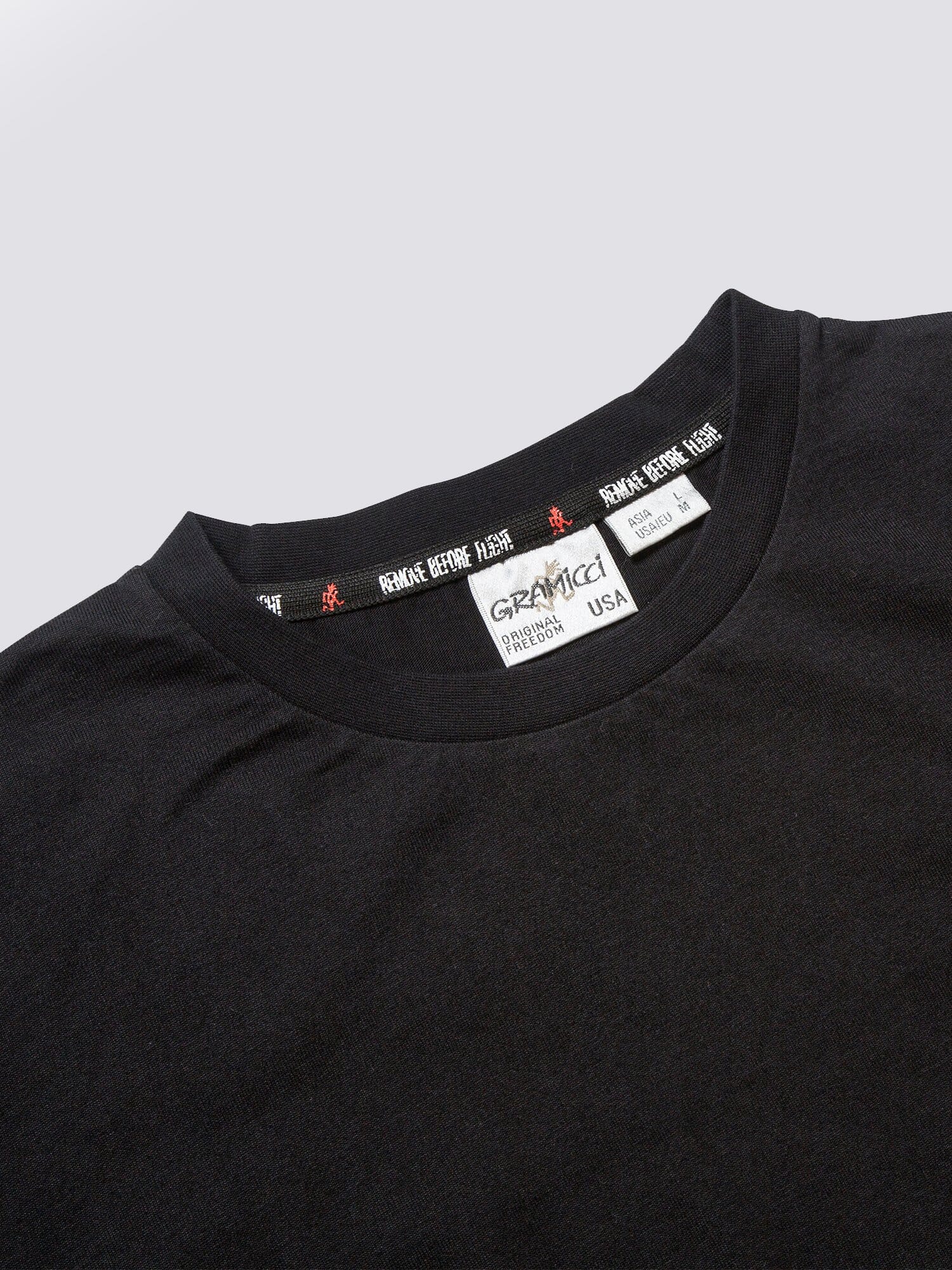 Gramicci X Alpha Cotton Cigar Pocket Tee by Alpha Industries, black crewneck collar, branded label with size and origin details, utility pocket on sleeve.