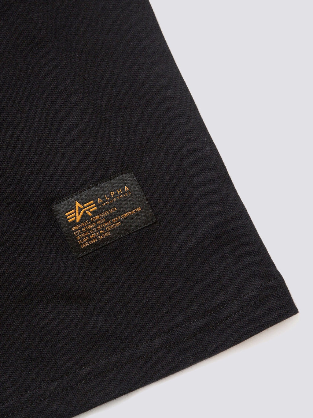 Alpha Industries Gramicci X MA-1 Cotton Cigar Pocket Tee, black, small rectangular label with gold text and logo near hem.
