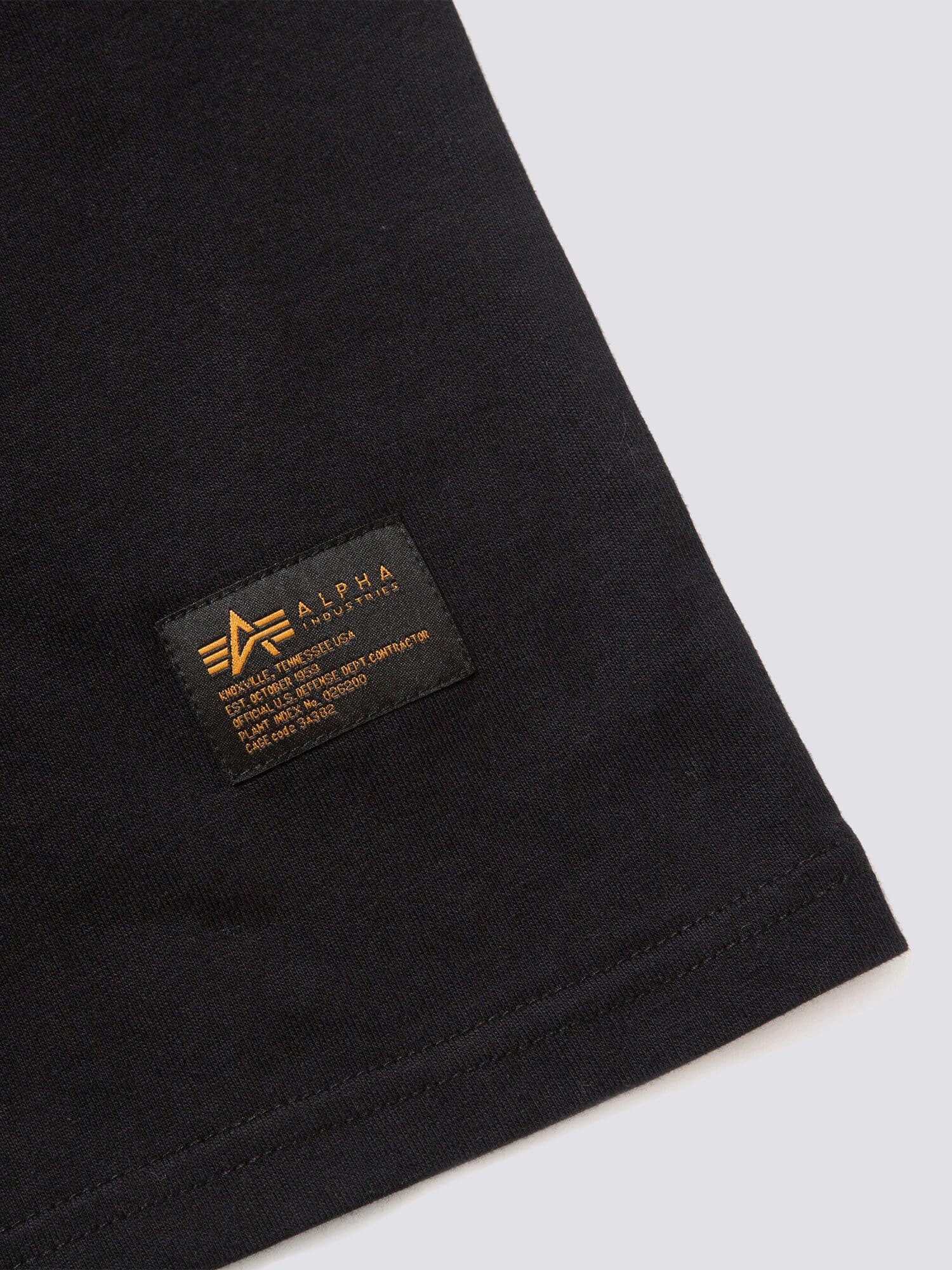 Alpha Industries Gramicci X MA-1 Cotton Cigar Pocket Tee, black, small rectangular label with gold text and logo near hem.
