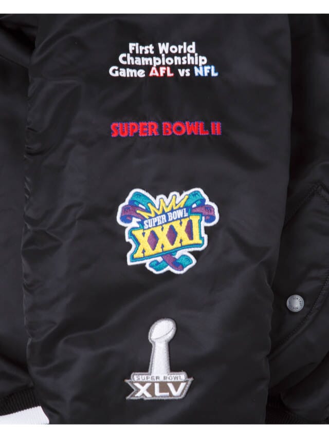 Introducing the Green Bay Packers X Alpha x New Era MA-1 Bomber Jacket by Alpha Industries, showcasing embroidered logos from the First World Championship Game AFL vs. NFL, as well as Super Bowl II, XXXI, and XLV. This exclusive piece celebrates football history while blending style and versatility with New Era x NFL craftsmanship.