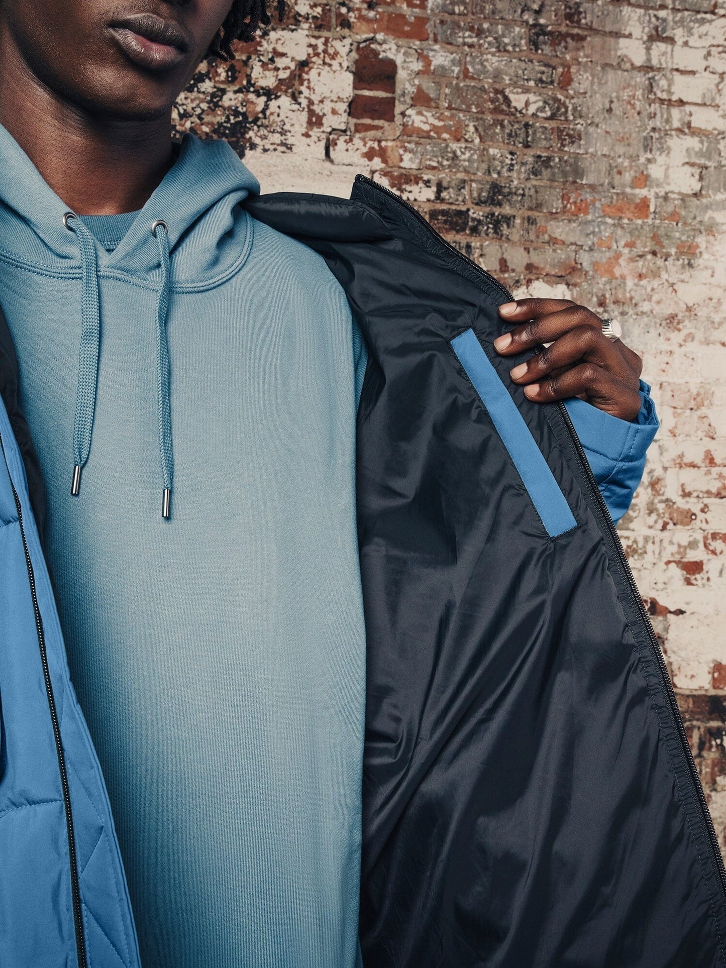 A person wearing the Hooded Puffer Jacket from Alpha Industries, Inc. highlights the inside pocket.