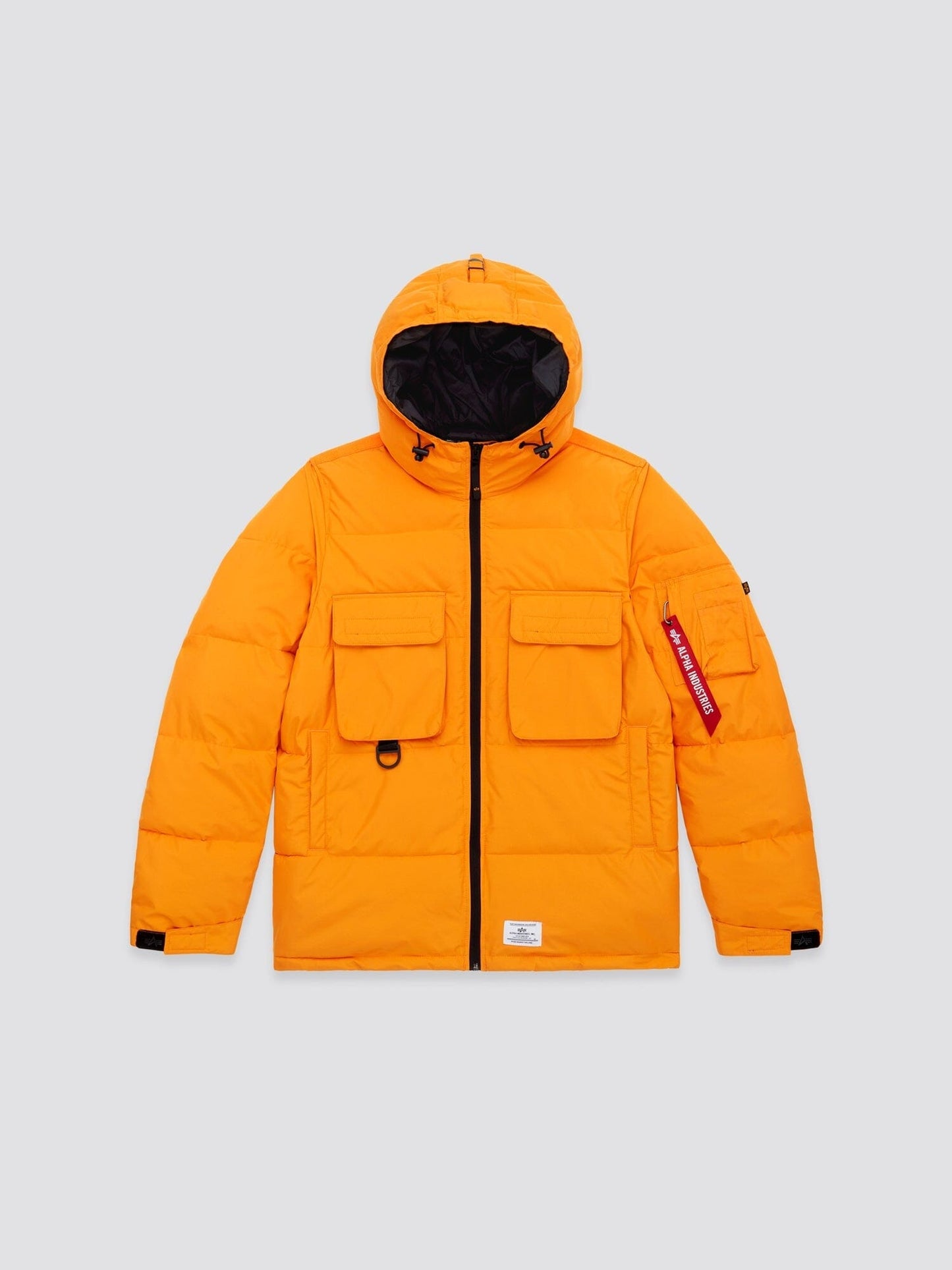 Muted orange Hooded Puffer Jacket by Alpha Industries, Inc. features an insulated hood, black zipper, large front pockets, and a small tag on the left sleeve.