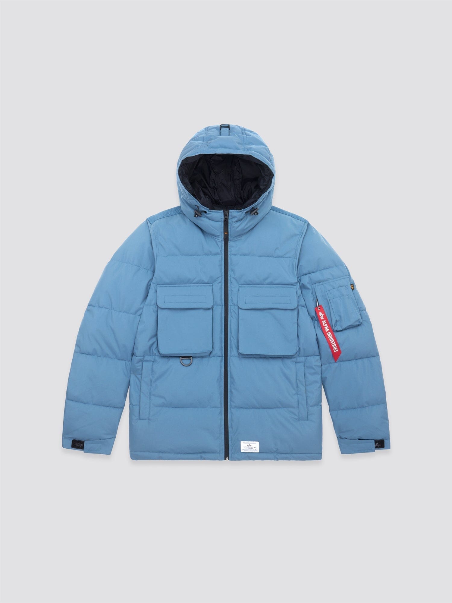 Slate blue Hooded Puffer Jacket by Alpha Industries, Inc., featuring an insulated hood and multiple front pockets, accented by a red tag on the left sleeve.