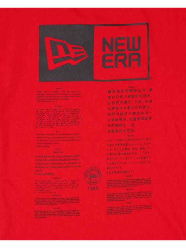 The Kansas City Chiefs x Alpha Industries x New Era T-Shirt, by Alpha Industries, is a vibrant red piece featuring the New Era logo prominently at the top. Below it, you'll find colorful text in multiple languages. This fashionable T-shirt is ideal for fans who appreciate both comfort and style while showcasing their team pride.
