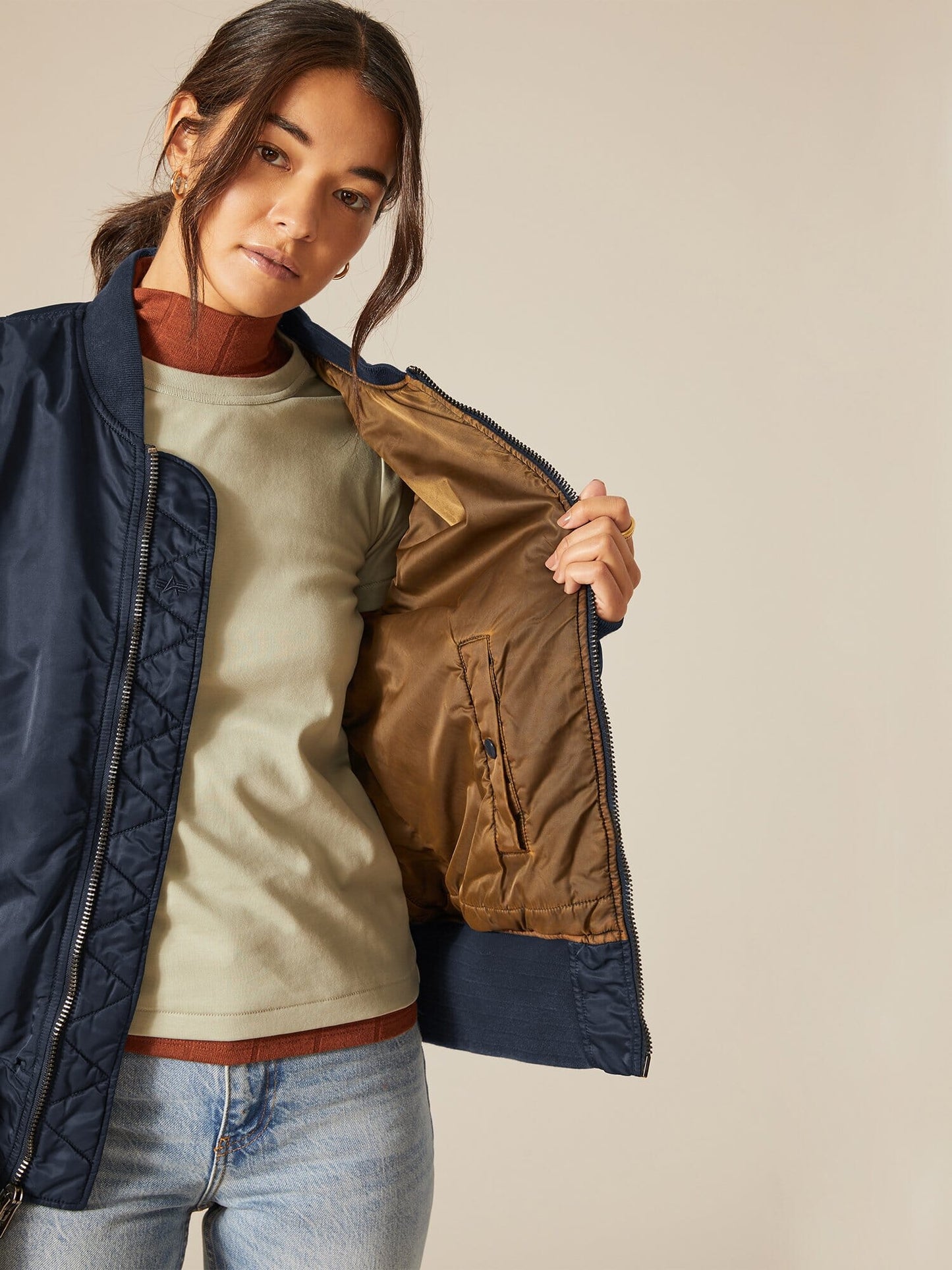 A person wearing a navy Alpha Industries MA-1 Bomber Jacket, showcasing the inner lining of the reversible jacket.