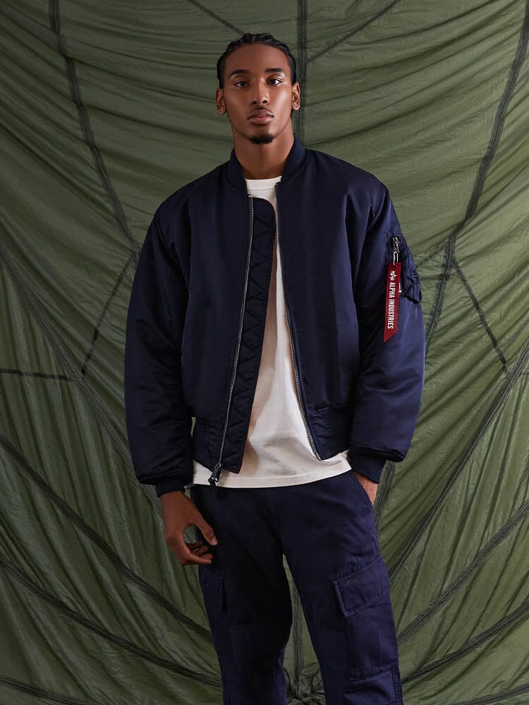 Alpha Industries MA-1 bomber jacket, white t-shirt, navy cargo pants; features include zip closure and ribbed cuffs.