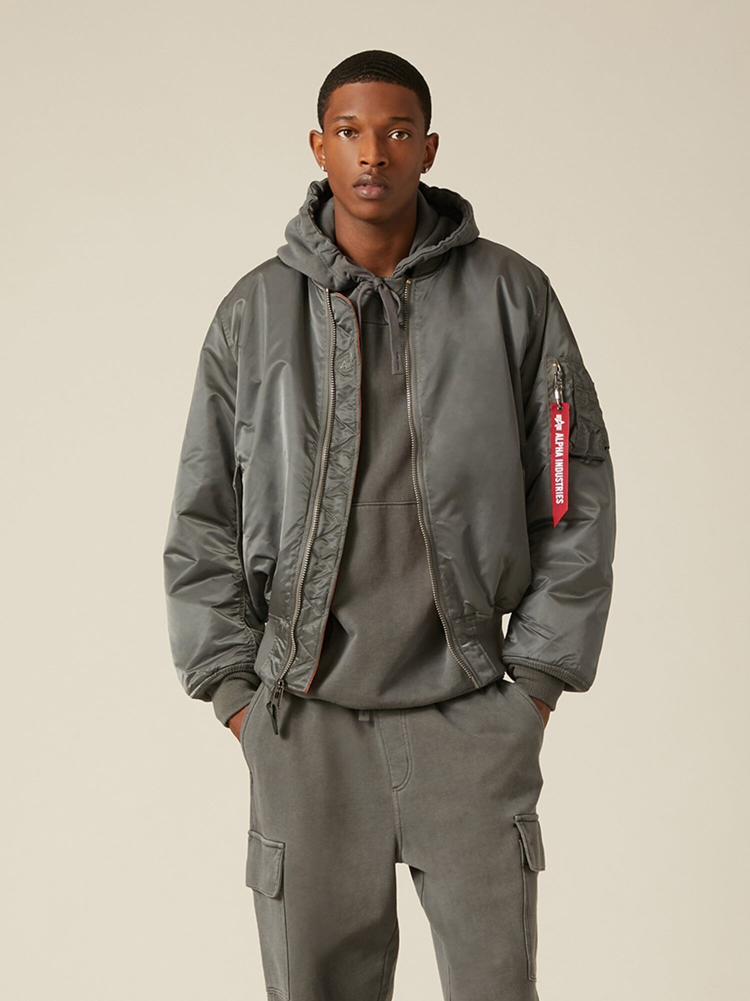 Alpha Industries MA-1 bomber jacket in gray flight nylon, over a gray hoodie and matching cargo pants.