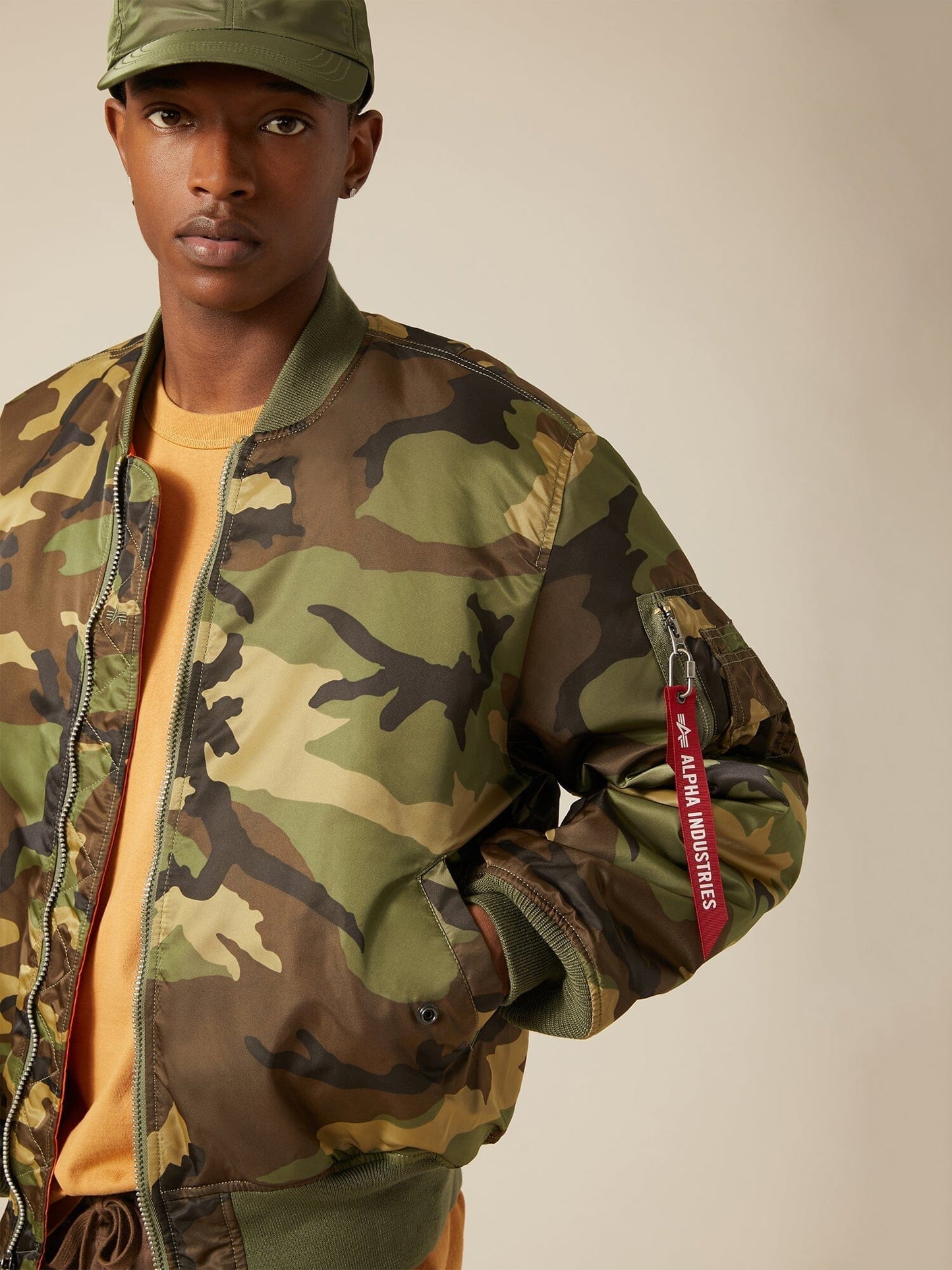 Close up view of MA-1 Bomber Jacket (Heritage) in Woodland Camo with male model. Sleeve and pocket view. By Alpha Industries.