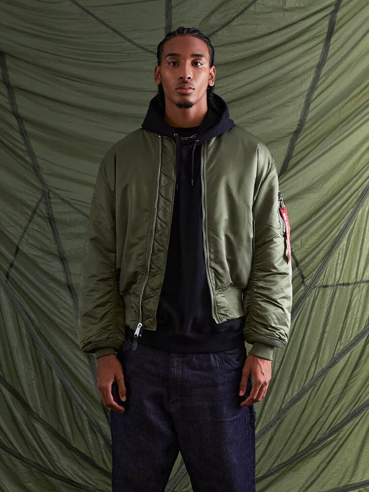 Alpha Industries MA-1 Bomber Jacket in flight nylon, black hoodie underneath, dark jeans.