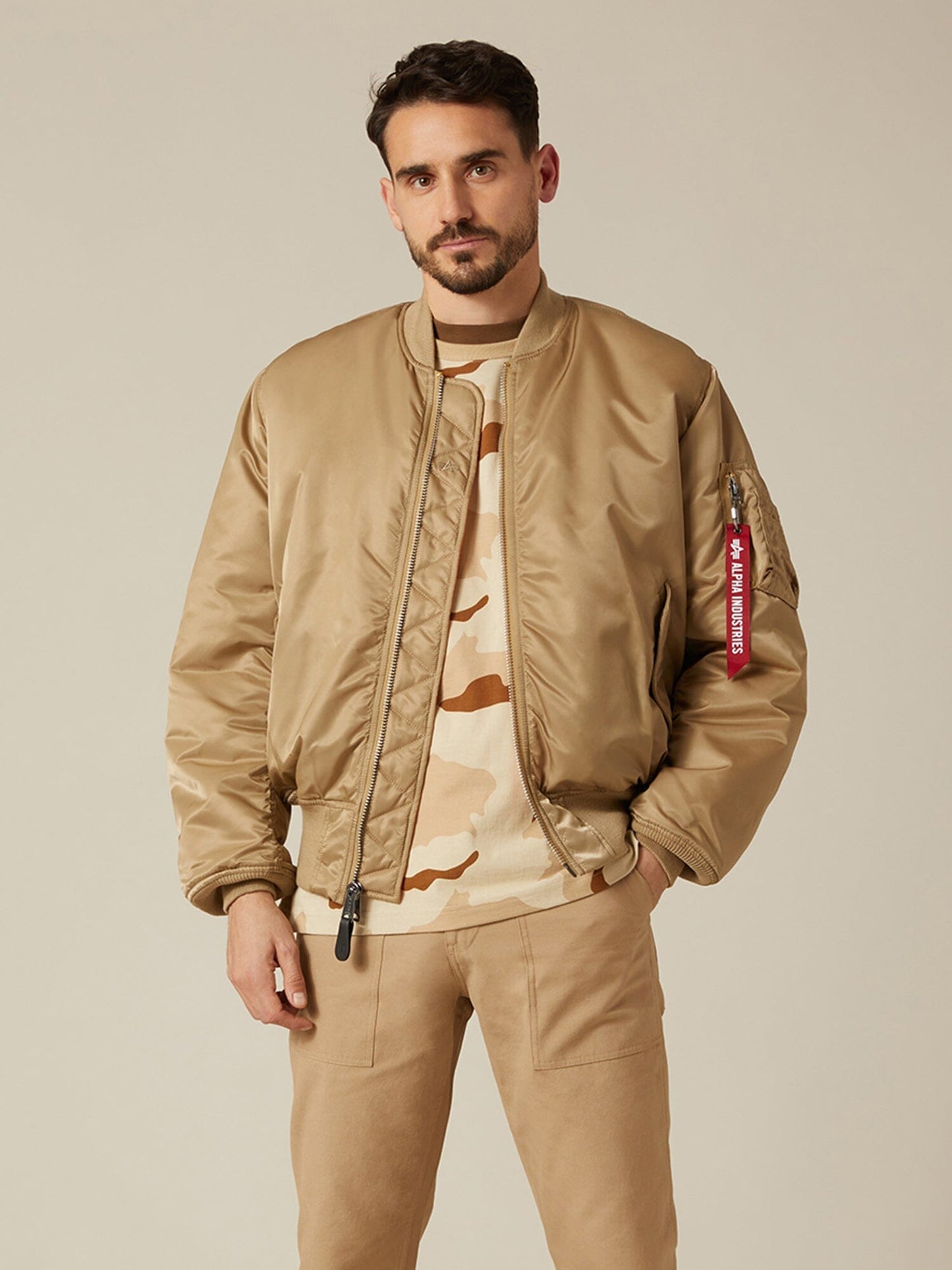 Front view of MA-1 Bomber Jacket (Heritage) in Khaki (Vintage) with male model. Knees up view. By Alpha Industries.