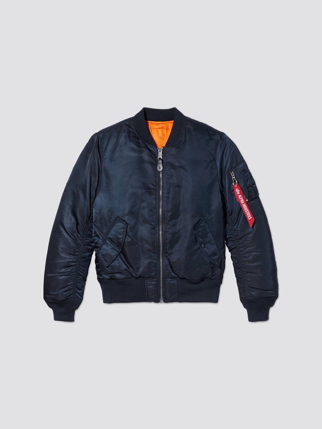 Front flat-lay view of replica blue Alpha Industries MA-1 Bomber Jacket Slim Fit showing orange lining and sleeve pocket with red tag.