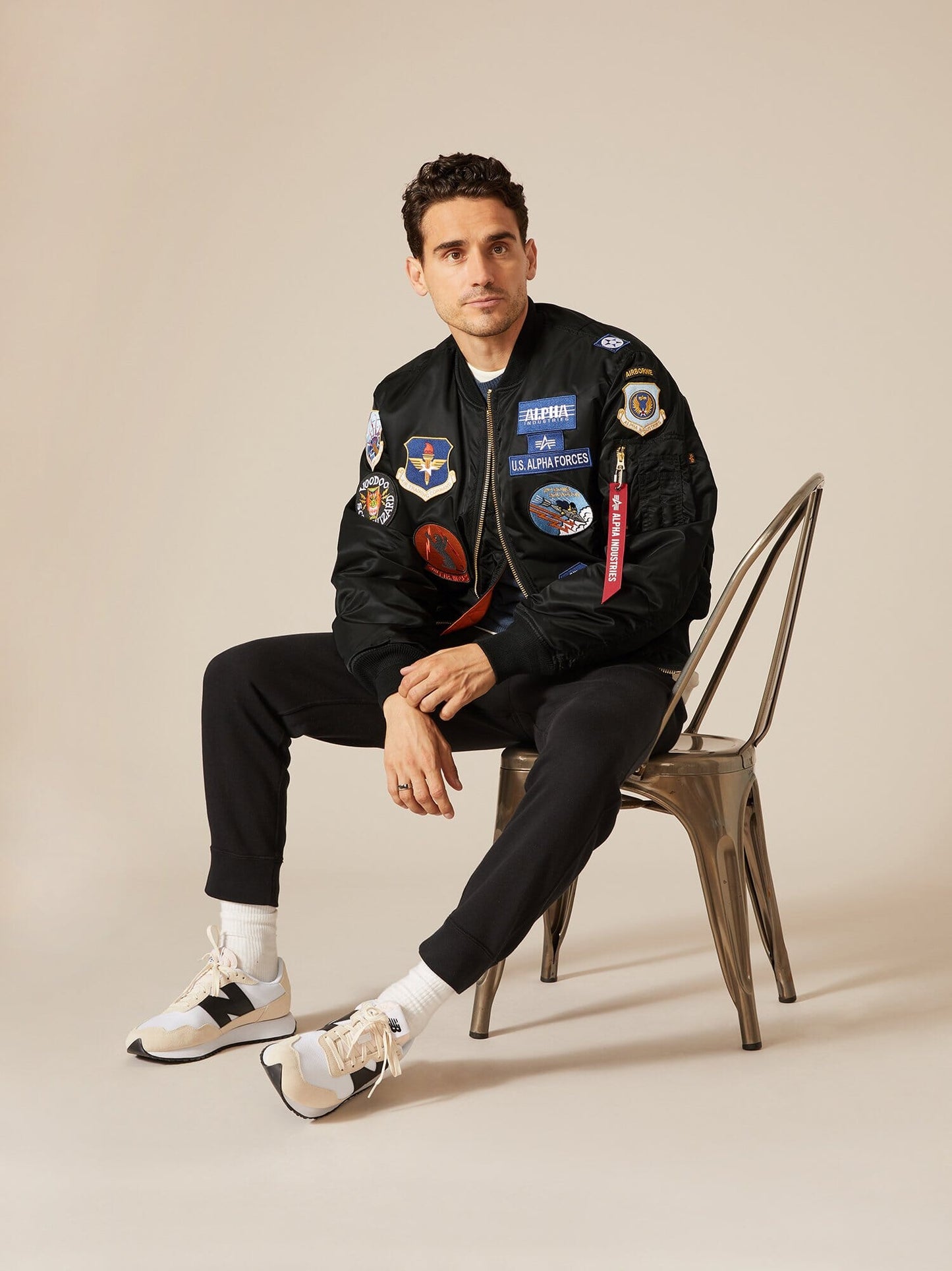 Alpha Industries MA-1 Squadron Bomber Jacket, black pants, sneakers; black color, bomber style, zip closure.
