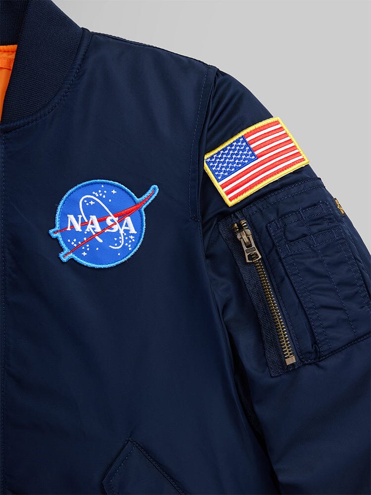 NASA MA-1 Bomber Jacket by Alpha Industries, navy blue with chest logo patch, embroidered American flag on sleeve, and MA-1 utility pocket.