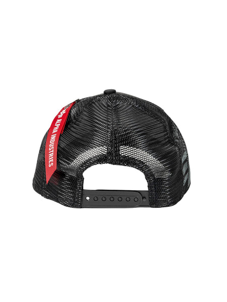 The image showcases the back view of a black mesh 940 A-Frame Trucker baseball cap by Alpha Industries, featuring an adjustable strap and a red tag labeled Alpha Industries.