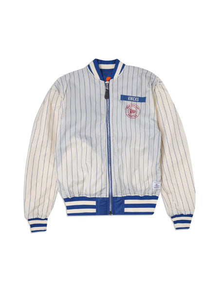 Introducing the New York Knicks X Alpha x New Era L-2B Bomber Jacket, a vintage-inspired piece from Alpha Industries and NE-NBA. This exclusive jacket features vertical pinstripes and showcases "Knicks" on the chest, complemented by a blue collar, cuffs, and waistband. Enhanced with authentic team patches.