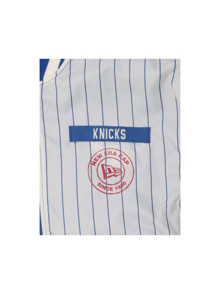 Close-up of a blue and white striped garment featuring the Knicks text and a distinctive red circular logo labeled New Era Cap Since 1920, reminiscent of the New York Knicks X Alpha X New Era L-2B Bomber Jacket from Alpha Industries.