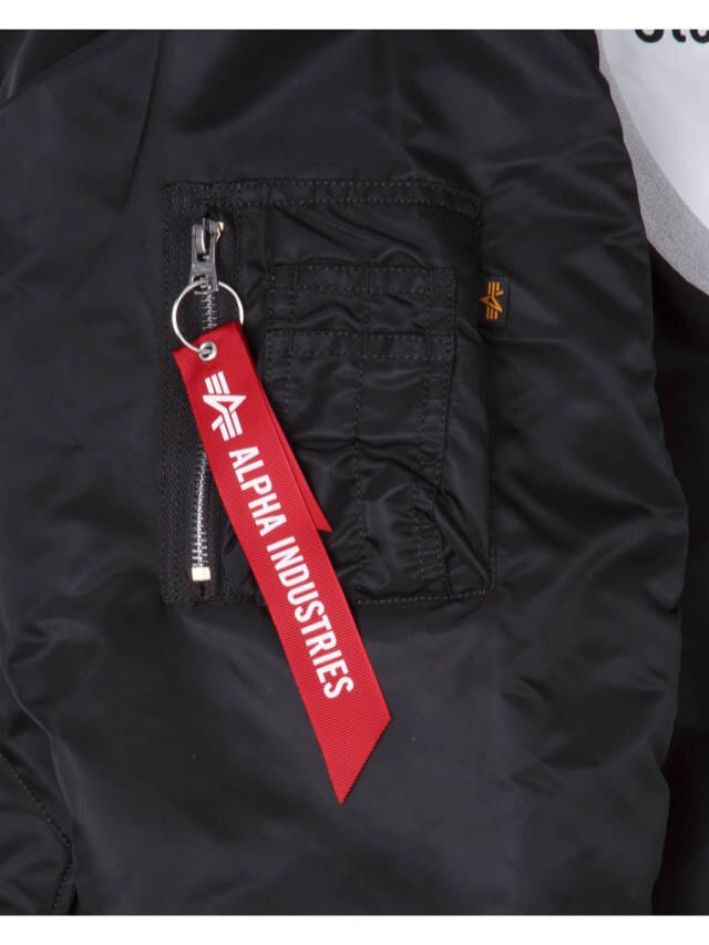 Close-up of the Pittsburgh Steelers x Alpha x New Era MA-1 Bomber Jacket pocket with a red tag attached to the zipper, featuring the Alpha Industries logo and name. This sleek piece is reversible, providing versatility for any look.