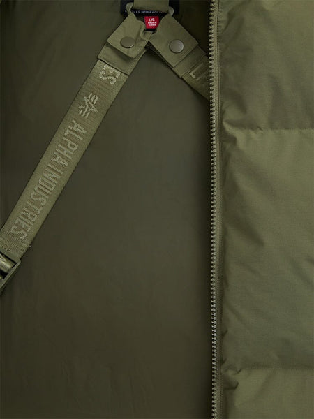 A close-up of the olive green Puffer Parka's interior showcases a zipper, snap buttons, and a strap printed with "Alpha Industries." 