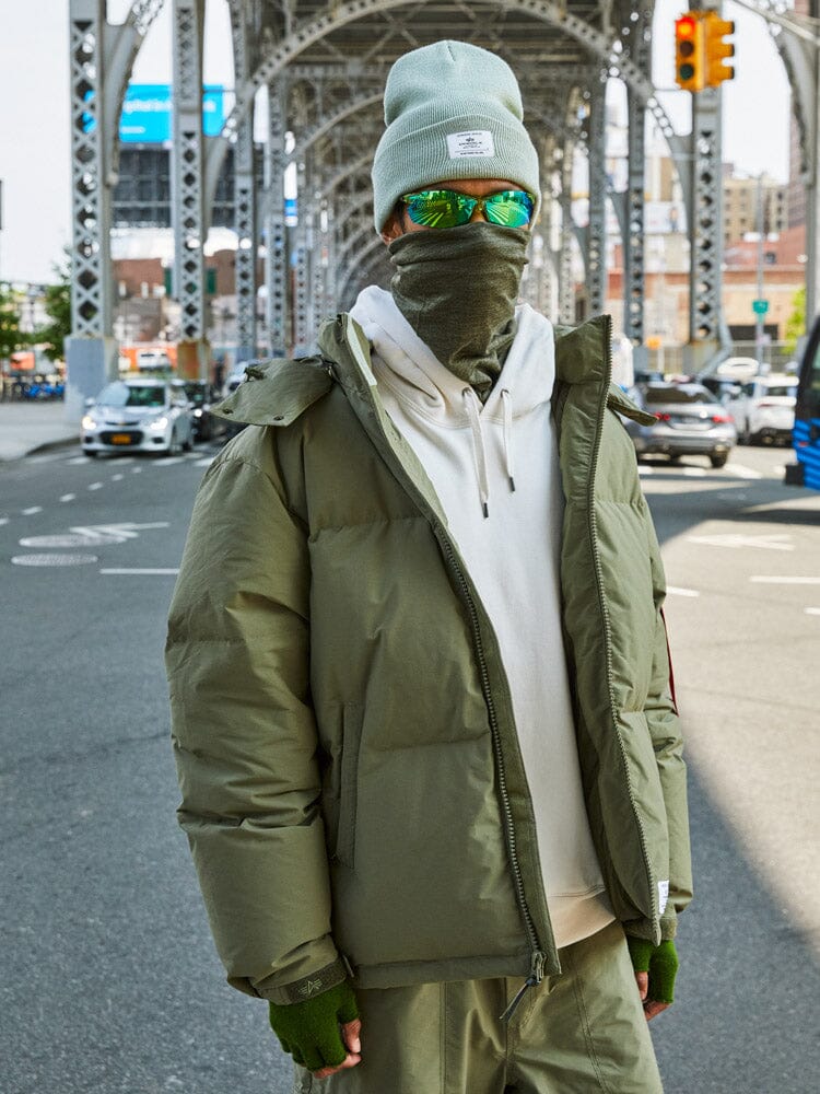 A person wearing the Puffer Parka in olive green by Alpha Industries.