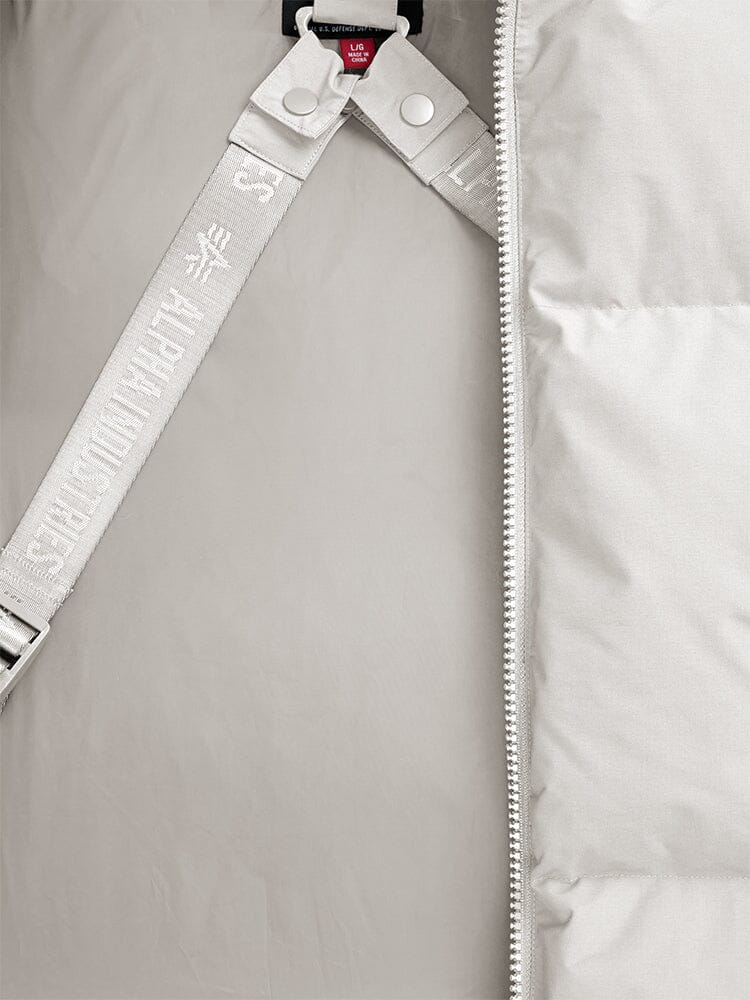 Close-up of the Alpha Industries Puffer Parka, showcasing a limestone padded design with a zipper and partially visible strap featuring embossed text.