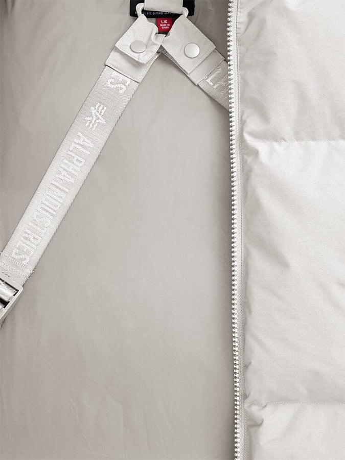Close-up of the Alpha Industries Puffer Parka, showcasing a limestone padded design with a zipper and partially visible strap featuring embossed text.