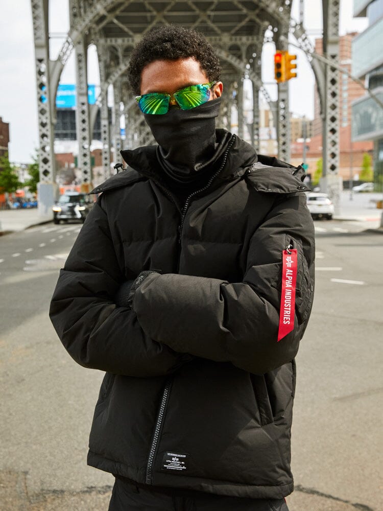 A person wearing the Puffer Parka in black by Alpha Industries.