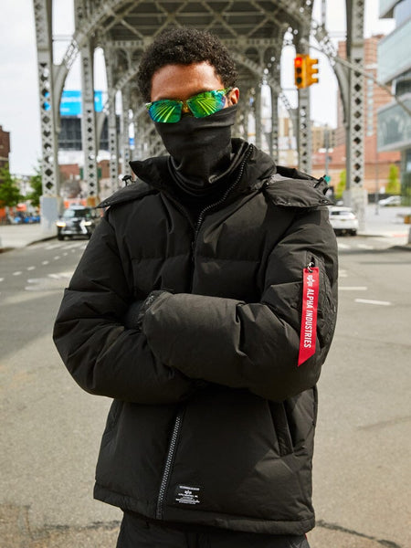 A person wearing the Puffer Parka in black by Alpha Industries.