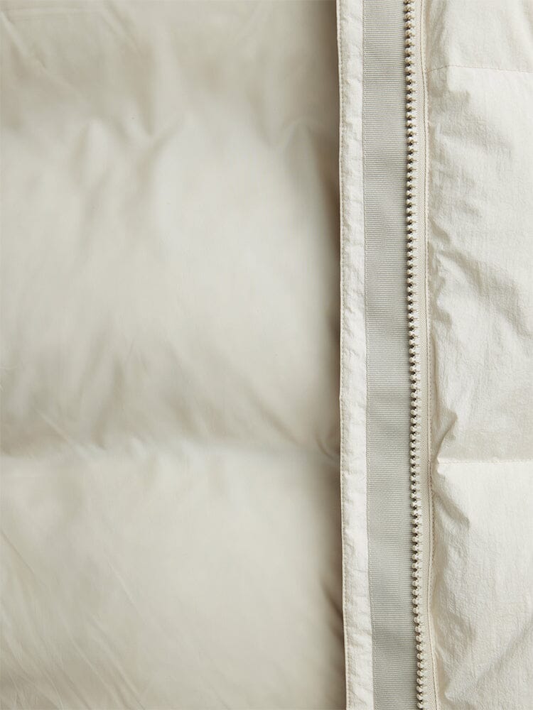 Close-up of the Sierra Short Puffer W by Alpha Industries, showcasing its light-colored quilted fabric with down fill, unzipped zipper, and water-resistant design.