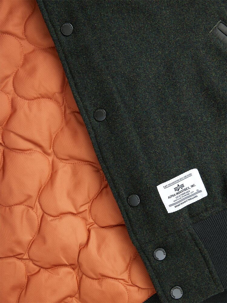 Alpha Industries Wool Varsity Bomber Jacket Gen II, orange nylon quilted lining, black snap buttons, white brand label, dark wool outer fabric.